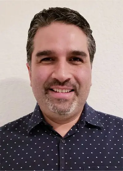 A man with a beard and mustache wearing a blue shirt.