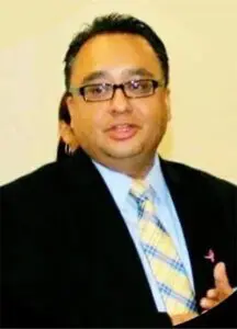 A man in a suit and tie standing up against a wall.