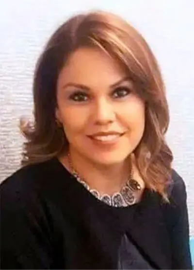 A woman with brown hair and wearing black is smiling.