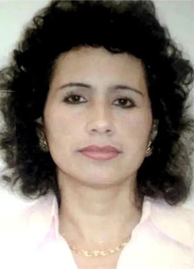 A woman with curly hair and pink shirt.