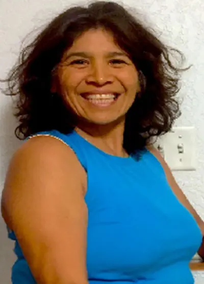 A woman smiling for the camera in front of a wall.