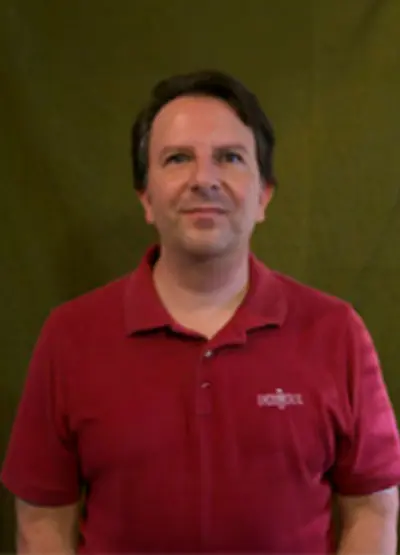 A man in red shirt standing next to green wall.