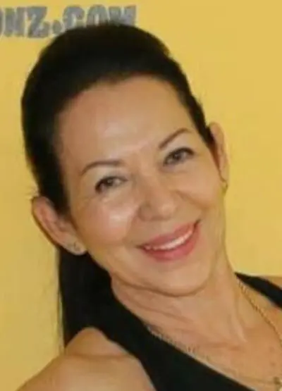 A woman smiling for the camera with her hair in a ponytail.