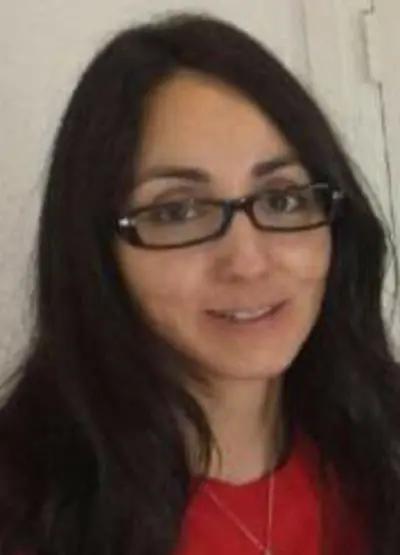 A woman with glasses is smiling for the camera.