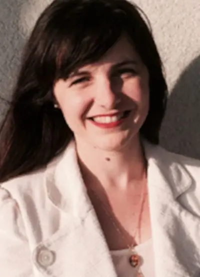 A woman in white jacket smiling for the camera.