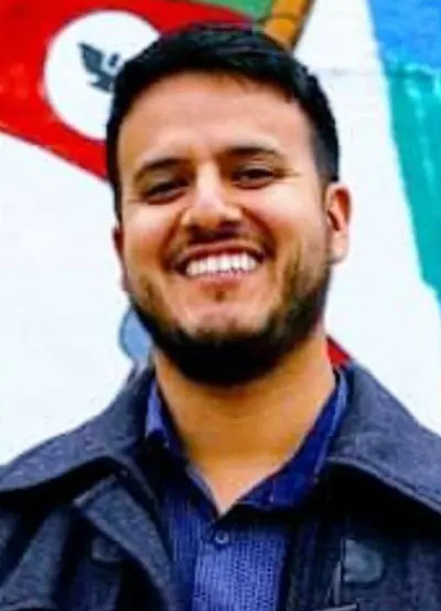 A man smiling for the camera in front of a wall.