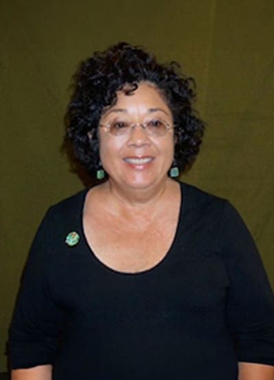 A woman with curly hair wearing glasses and black shirt.