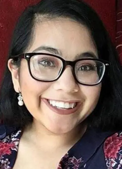 A woman with glasses smiling for the camera.