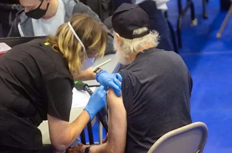 A person getting vaccinated by someone in blue gloves.