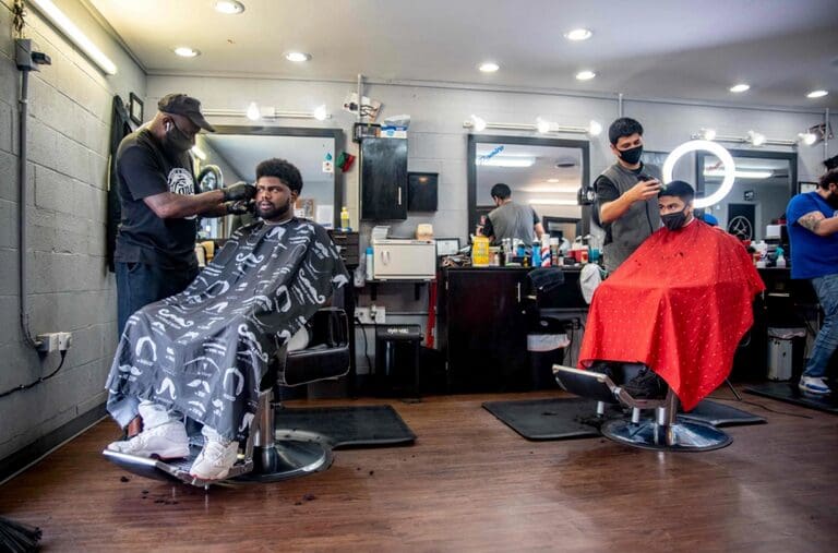 A barber shop with several men getting their hair cut.