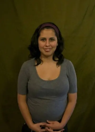 A woman in grey shirt smiling for the camera.